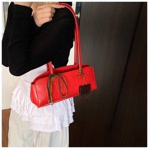 Détail d'un sac à bandoulière en cuir rouge avec ruban décoratif et pendentif en forme de coeur