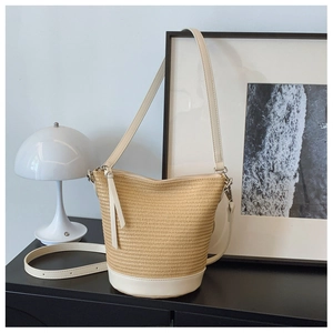 Vue détaillée du sac seau en paille avec garniture en cuir crème et longue bandoulière