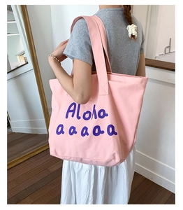 Pink canvas tote bag with purple Aloha print worn by a model in a minimal interior