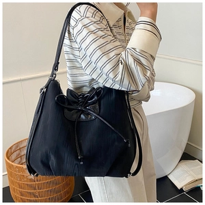 Detail of a black hobo shoulder bag with a drawstring closure and a decorative bow tie