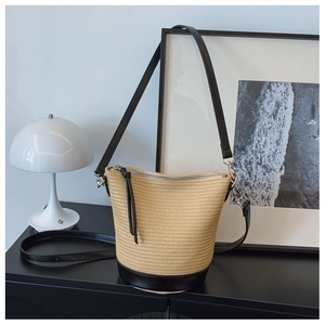 Vue détaillée du sac seau en paille tressée avec bordure en cuir noir et fermeture éclair