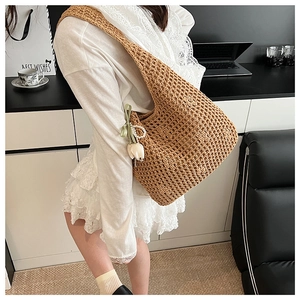 Detail of woven straw tote bag with elegant tulip charm and pearl ribbon accessory