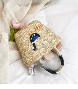 Top view of woven straw bucket bag showing spacious interior with cosmetics and embroidery