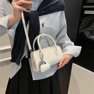 Detail of white mini bowling bag with heart-shaped charm and adjustable strap