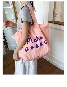 Detail of light pink canvas tote bag with purple Aloha text for summer fashion