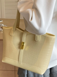 Minimalist beige tote bag with crocodile texture and gold lock shown on shoulder
