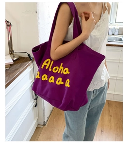Detailed shot of large purple canvas tote bag with yellow Aloha text on female model