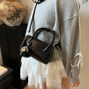 Detail of black glossy PU leather bowling bag with heart charm and shoulder strap