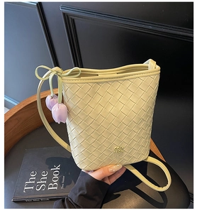 Detail of light yellow woven bucket bag with leather tulip pendant and gold logo