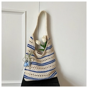 Detail of striped crochet tote bag with blue ribbon flower and pearl bag charm