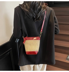 Detail of burgundy leather trim and woven straw texture on a mini bucket crossbody bag