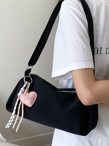 Sac polochon en toile noire avec breloque cœur porté par un mannequin de profil