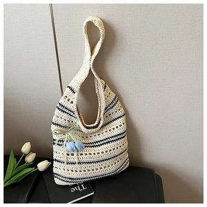 Detailed knit texture of a beige woven tote bag with black stripes and flower charm