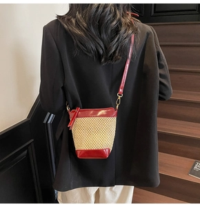 Detail of straw bucket bag with red PU leather trim and gold metal hardware
