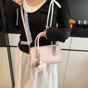 Detail view of pink PU leather bowling bag with heart charm and shoulder strap
