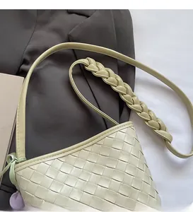Detail view of beige woven leather bag with decorative twisted shoulder strap on a grey suit