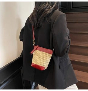 Detail of red leather trim and straw woven texture on a stylish summer bucket bag