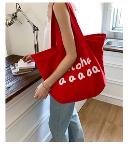 Detail of red canvas tote bag with white aloha text print for summer travel