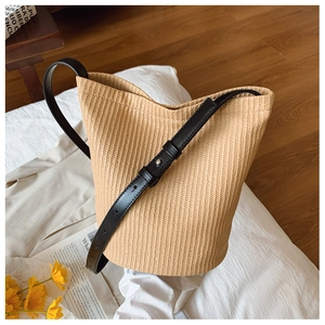 Detail einer geflochtenen Strohtasche mit schwarzem Lederband und feiner Textur