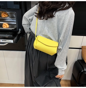 Détail du petit sac bandoulière jaune en cuir grainé avec rabat minimaliste et texture fine