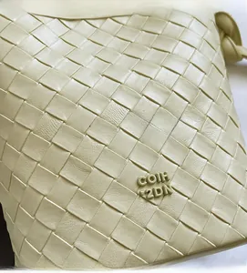Close-up of beige woven leather bucket bag featuring a detailed interlaced grain texture