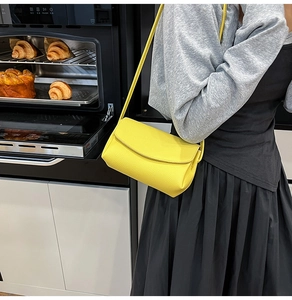 Vue détaillée du sac bandoulière en cuir grainé jaune porté par un mannequin en cuisine
