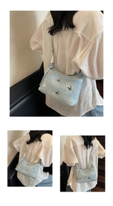 Detail der hellblauen Denim-Tasche mit Schmetterlingsanhängern und silbernem Schultergurt