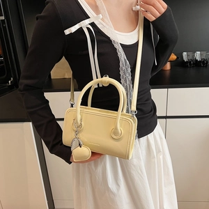 Detail of light yellow PU leather bowling bag with heart charm in a kitchen setting