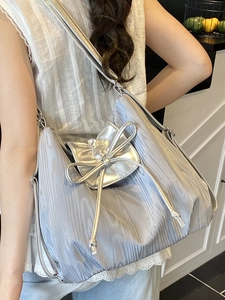 Silberne Falten-Tragetasche mit großer Schleife und Metallic-Finish am Modell