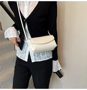 Détail de la texture cuir grainé blanc crème sur un sac à bandoulière chic à rabat