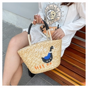 Close-up of handmade straw bucket bag featuring a cute duck and Hello embroidery