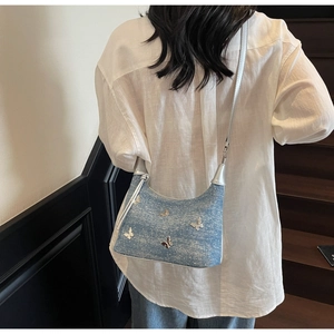 Detailansicht der hellblauen Denim-Schultertasche mit silbernen Schmetterlings-Metall-Deko