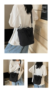 Detailed view of a black canvas tote bag with a round metal badge and nylon strap