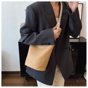 Detail der handgewebten Stroh-Eimertasche mit verstellbarem Lederriemen am Modell