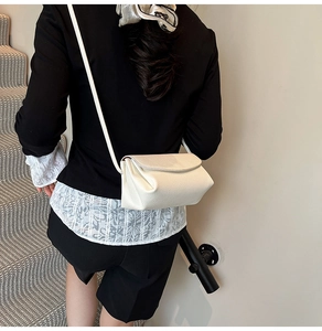 Détail du sac à bandoulière en cuir blanc avec texture grainée et design élégant minimaliste