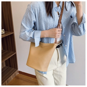 Detail einer geflochtenen Bucket Bag mit braunem Lederriemen und feiner Textur