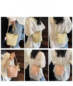 Detail of woven texture bucket bag with tulip charm and braided strap in beige and pink
