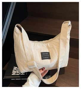 Close-up of the adjustable strap and buckle on the beige crescent shoulder bag