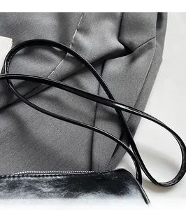 Detailansicht der glänzend schwarzen Zylindertasche mit verstellbarem glattem Schulterriemen