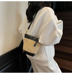 Detail of hand-woven straw bucket bag with black leather trim and zipper closure