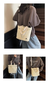 Detail view of a beige canvas drawstring tote bag with a metal logo and detachable strap