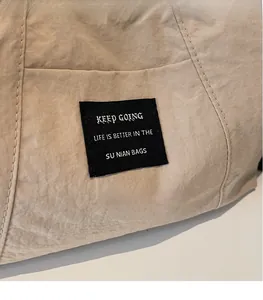 Dettaglio borsa tote minimalista beige che mostra cuciture e etichetta nera del marchio