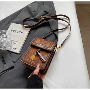 Detail of vintage brown plaid crossbody bag with golden hardware and tassel charm on grey suit