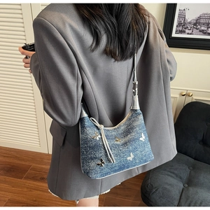 Detail einer blauen Denim Hobo Tasche mit silbernen Schmetterling-Akzenten als Schultertasche