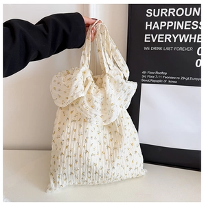 Détail d'un sac cabas plissé blanc avec motifs de petites fleurs jaunes et texture douce