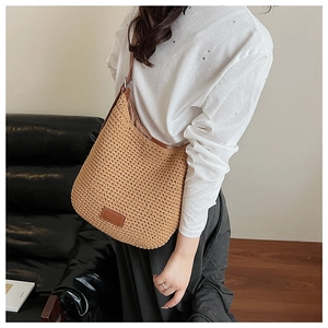 Detail of handwoven cotton hobo bag featuring brown leather logo patch and thin strap