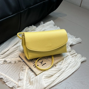 Détail du sac à bandoulière en cuir jaune vif avec rabat incurvé minimaliste