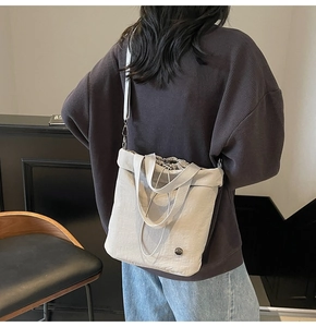 Detail view of stylish drawstring tote bag in cream nylon with crossbody strap on model