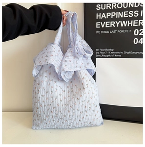 Détail d'un sac cabas en toile à fleurs bleu clair avec bords à volants et tissu gaufré