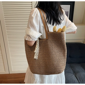 Detail of hand-woven straw tote with leather handles and white lace decorative ribbon